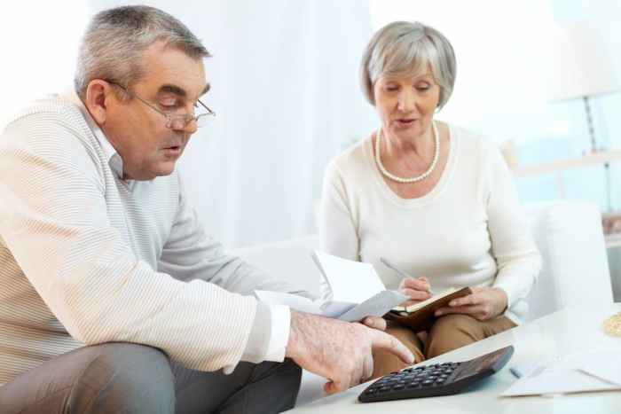 Woman and man talking over calculator and documents representing financial adviser and client for financial mis-selling.